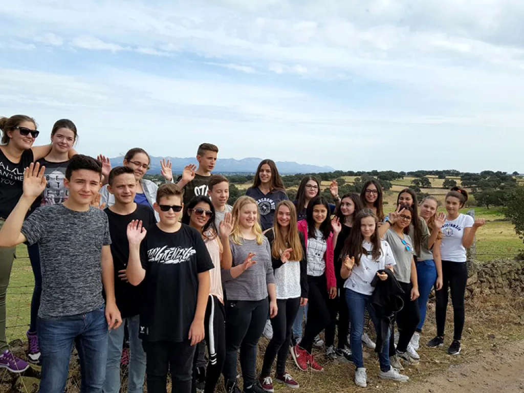 Die Reisegruppe steht winkend auf einem Feldweg vor weiter Landschaft.